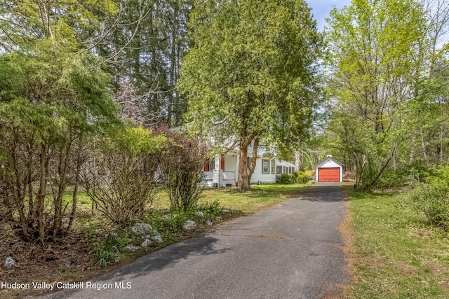 view of front of property featuring a detached garage, driveway, an outdoor structure, and a front lawn