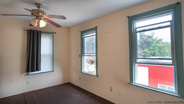 empty room with ceiling fan and dark carpet