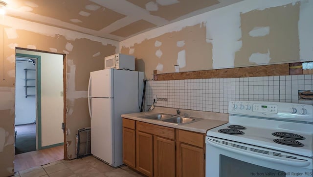 kitchen with light countertops, white appliances, a sink, and decorative backsplash