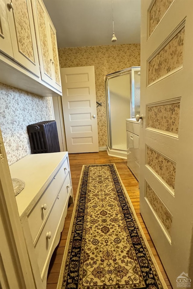 hall featuring light wood-style floors, washer / clothes dryer, and wallpapered walls