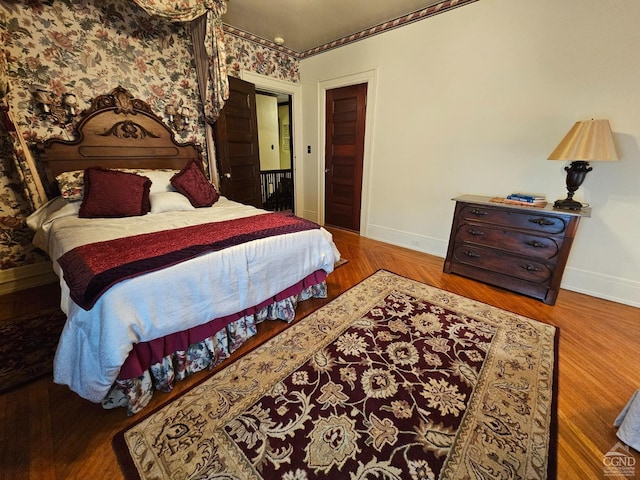 bedroom with baseboards, crown molding, and wood finished floors