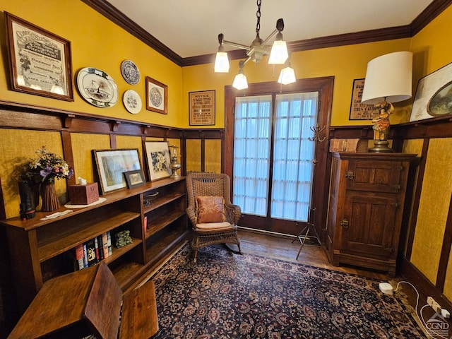 living area featuring ornamental molding, a wainscoted wall, wood finished floors, and a decorative wall