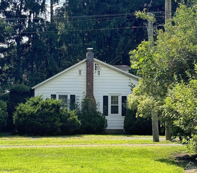 view of side of property with a lawn and a chimney