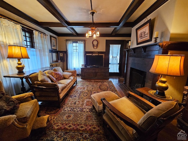 living area featuring a fireplace with flush hearth, coffered ceiling, wood finished floors, beamed ceiling, and a wainscoted wall