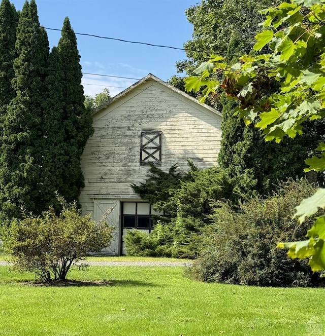 view of side of property with a barn, a lawn, and an outbuilding