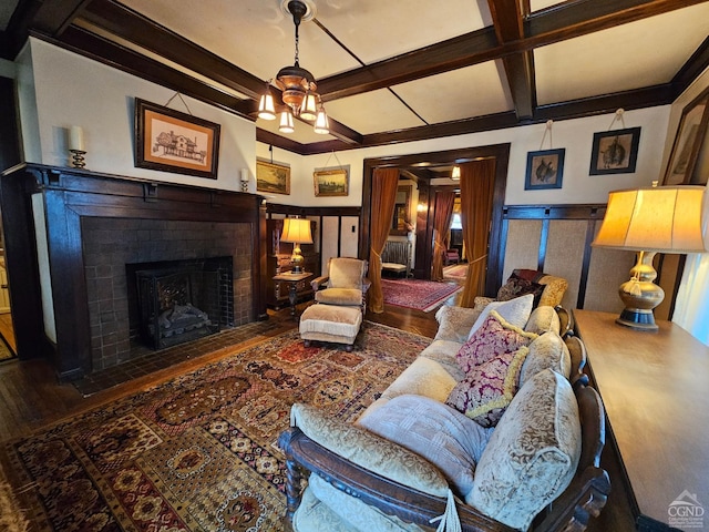 living room featuring wood finished floors, a brick fireplace, beam ceiling, coffered ceiling, and a wainscoted wall