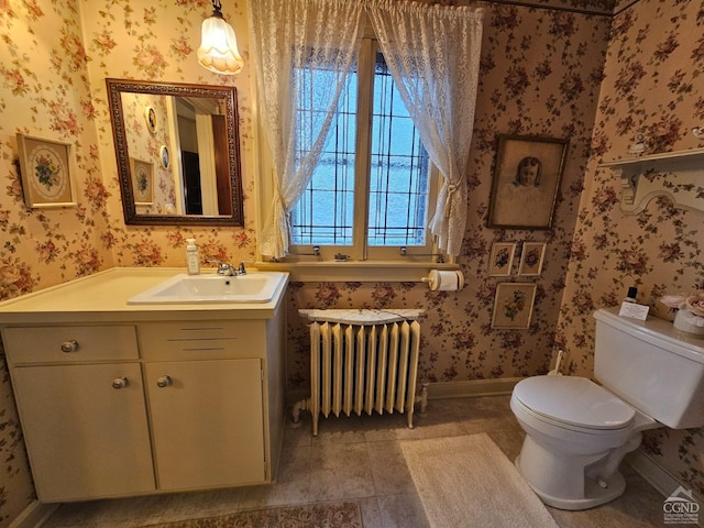 half bath featuring radiator heating unit, wallpapered walls, toilet, vanity, and baseboards