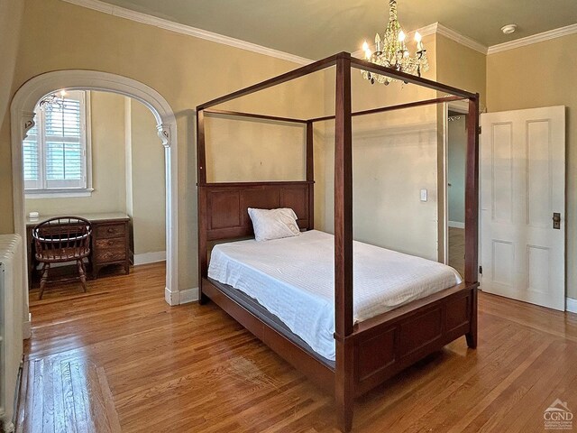 517-519 Washington St, Hudson, NY 12534 - bedroom featuring a chandelier, wood finished floors, crown molding, baseboards, and arched walkways