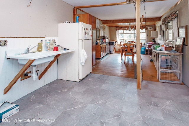 kitchen with wood walls, white refrigerator, and light hardwood / wood-style flooring