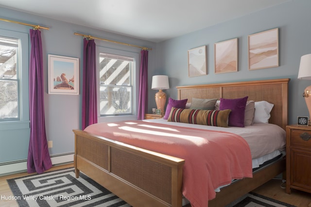 bedroom featuring hardwood / wood-style flooring and a baseboard heating unit