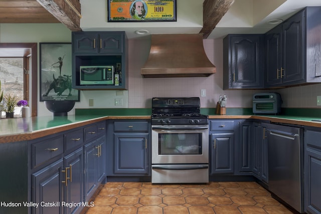 kitchen featuring appliances with stainless steel finishes, blue cabinets, tasteful backsplash, beamed ceiling, and custom range hood