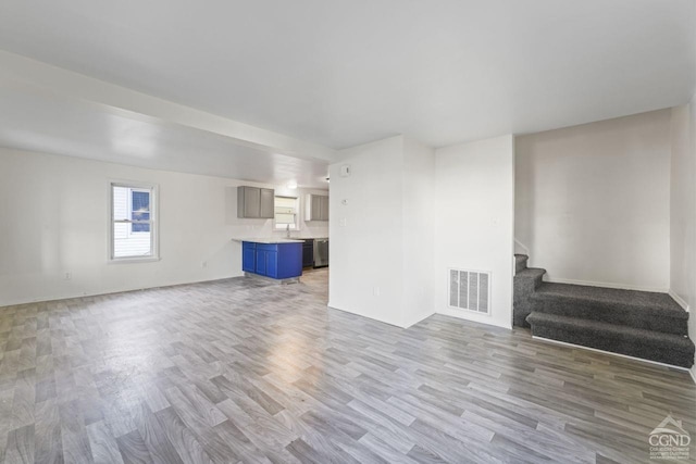 124 Cottage St, Ravena, NY 12143 - unfurnished living room with stairs, wood finished floors, and baseboards