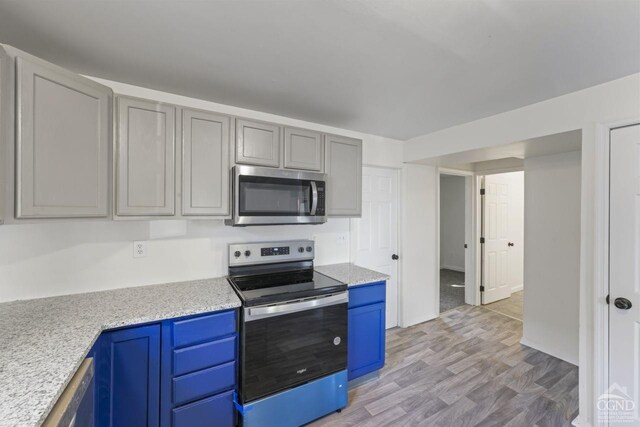 124 Cottage St, Ravena, NY 12143 - kitchen with stainless steel appliances, light wood-style flooring, and blue cabinetry