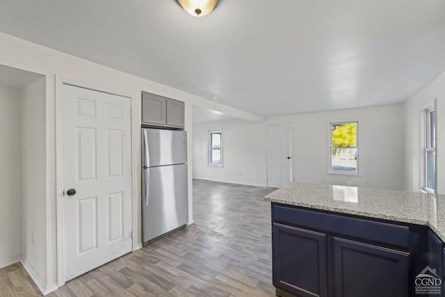 124 Cottage St, Ravena, NY 12143 - kitchen featuring freestanding refrigerator, light wood-type flooring, light stone countertops, open floor plan, and a peninsula