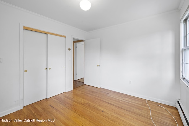 293 Pine Bush Rd, Stone Ridge, NY 12484 - unfurnished bedroom featuring a baseboard heating unit, ornamental molding, light wood-type flooring, and a closet