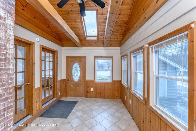 entrance foyer featuring lofted ceiling with skylight, wainscoting, wooden ceiling, and a healthy amount of sunlight