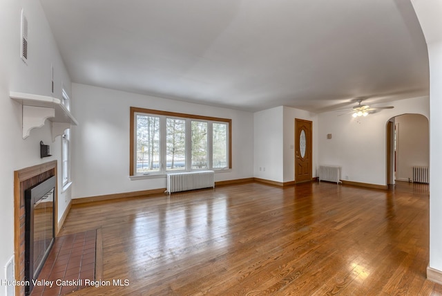 unfurnished living room with a fireplace, hardwood / wood-style flooring, and radiator