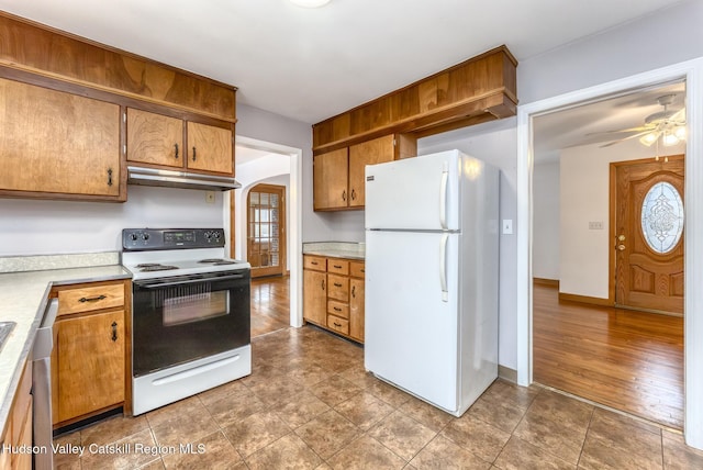 kitchen with arched walkways, electric stove, freestanding refrigerator, light countertops, and under cabinet range hood