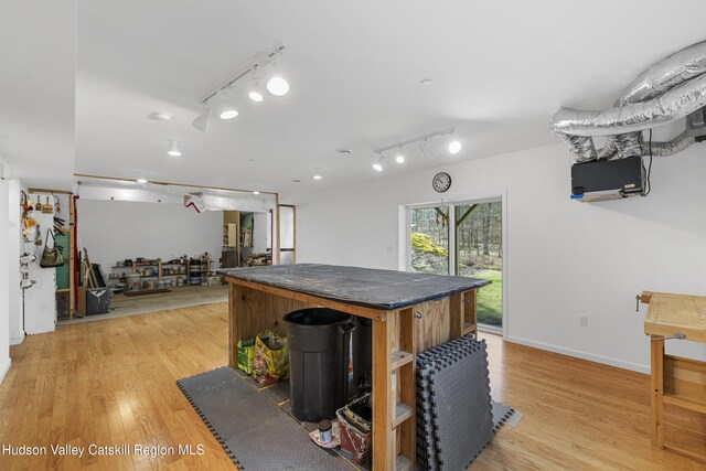 kitchen with light wood-style flooring, dark countertops, rail lighting, and baseboards
