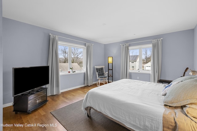 bedroom with baseboards, multiple windows, and wood finished floors