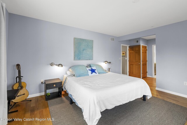 bedroom featuring baseboards, visible vents, and wood finished floors
