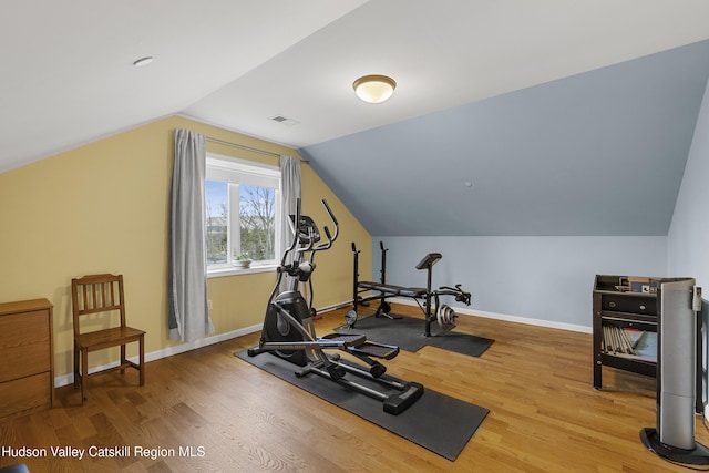 workout area featuring baseboards, visible vents, wood finished floors, and lofted ceiling