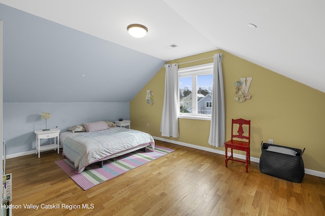 bedroom featuring baseboards, wood finished floors, and vaulted ceiling
