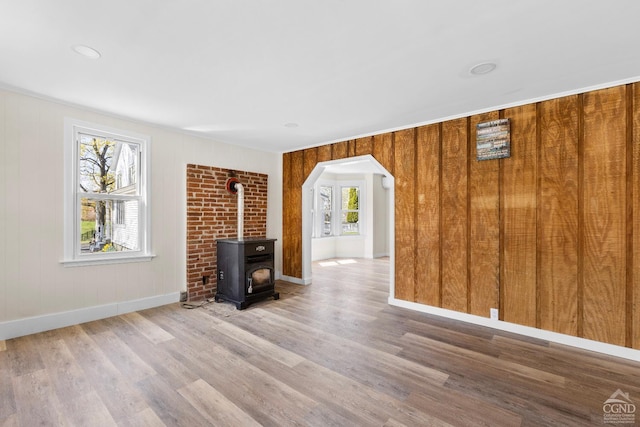4 Lawrence Ave, Coxsackie, NY 12051 - unfurnished living room featuring wood finished floors, a wood stove, baseboards, and arched walkways