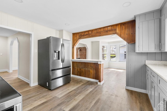 4 Lawrence Ave, Coxsackie, NY 12051 - kitchen featuring stainless steel fridge with ice dispenser, arched walkways, light wood finished floors, gray cabinets, and baseboards