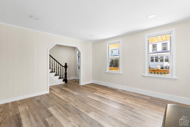 4 Lawrence Ave, Coxsackie, NY 12051 - unfurnished living room featuring wood finished floors, arched walkways, stairway, baseboards, and crown molding