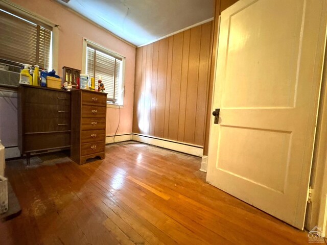 417 State St, Hudson, NY 12534 - bedroom featuring wood-type flooring, a baseboard radiator, and wooden walls
