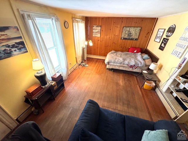 417 State St, Hudson, NY 12534 - living area featuring wood finished floors, baseboard heating, baseboards, ornamental molding, and wood walls