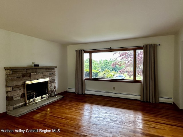 living room with wood-type flooring, a stone fireplace, and a baseboard heating unit