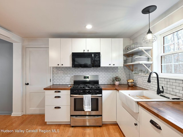 kitchen with butcher block counters, gas range, pendant lighting, and white cabinetry