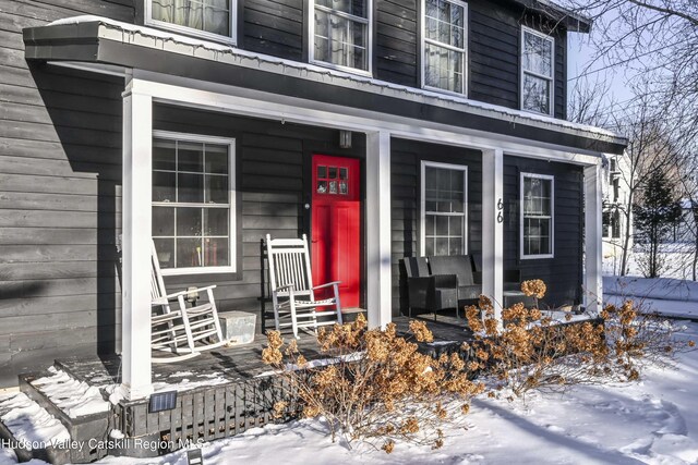 snow covered property entrance featuring a porch