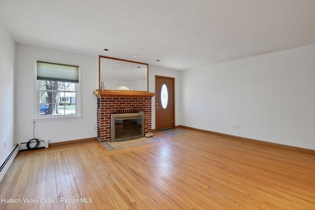 unfurnished living room with a baseboard radiator, baseboards, a brick fireplace, and hardwood / wood-style flooring