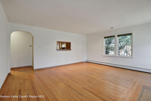 spare room with recessed lighting, arched walkways, a baseboard heating unit, baseboards, and light wood-style flooring