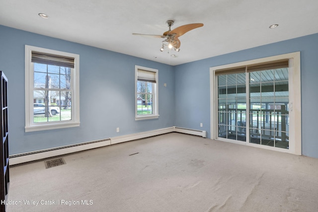 spare room featuring baseboard heating, ceiling fan, carpet floors, and plenty of natural light