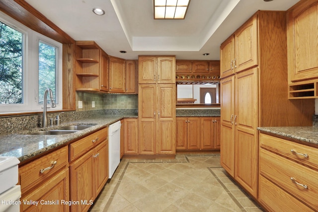 kitchen featuring light stone counters, open shelves, a sink, dishwasher, and a tray ceiling