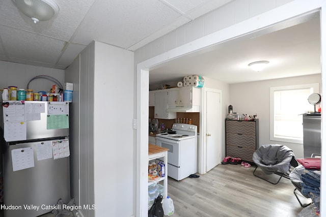 kitchen featuring white cabinets, white range with electric stovetop, light countertops, light wood-style floors, and water heater