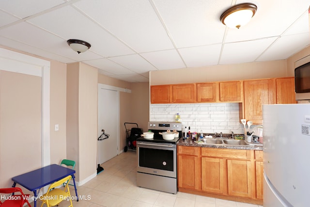 kitchen with a paneled ceiling, freestanding refrigerator, stainless steel electric stove, tasteful backsplash, and a sink