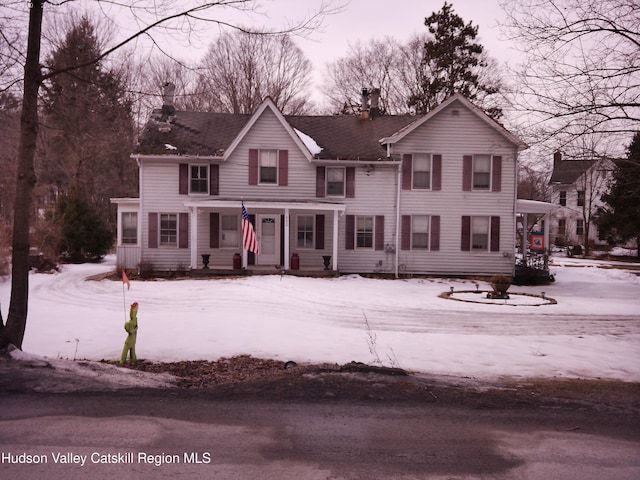 view of front facade with a carport, covered porch, and a chimney