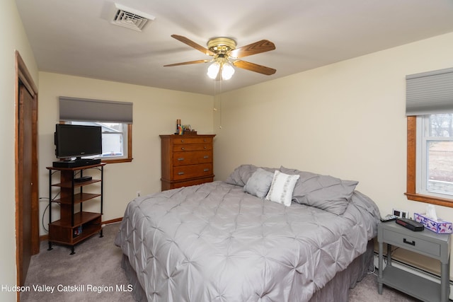 carpeted bedroom with ceiling fan, a closet, and a baseboard heating unit