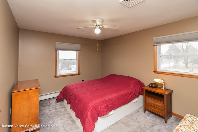 bedroom featuring ceiling fan, multiple windows, light carpet, and a baseboard radiator