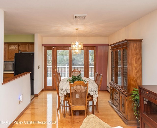 dining room with light hardwood / wood-style flooring, baseboard heating, and a notable chandelier