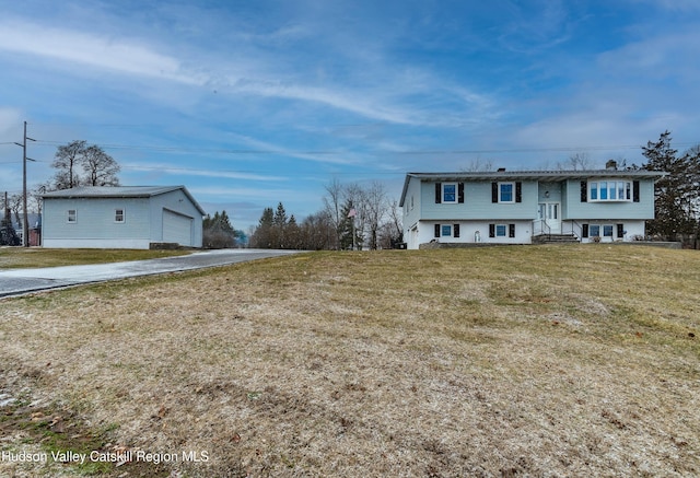 raised ranch with a front lawn, an outdoor structure, and a garage