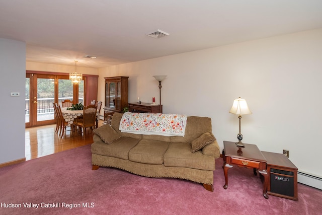 living room with carpet, a notable chandelier, and a baseboard heating unit