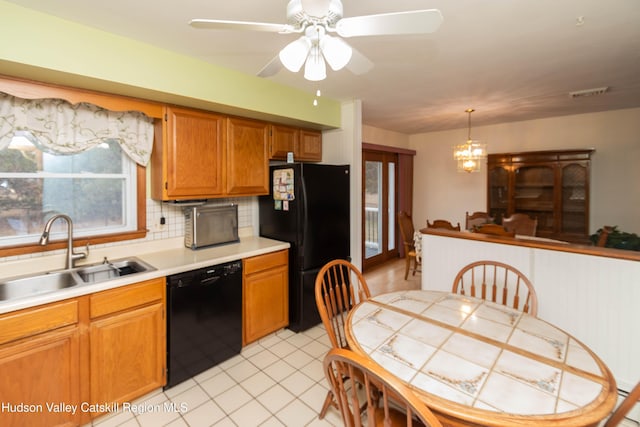 kitchen with sink, tasteful backsplash, pendant lighting, black appliances, and ceiling fan with notable chandelier