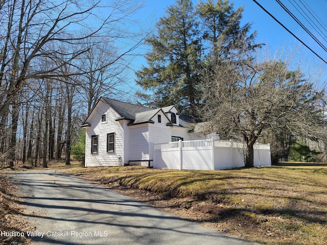 view of property exterior with driveway, fence, and a yard