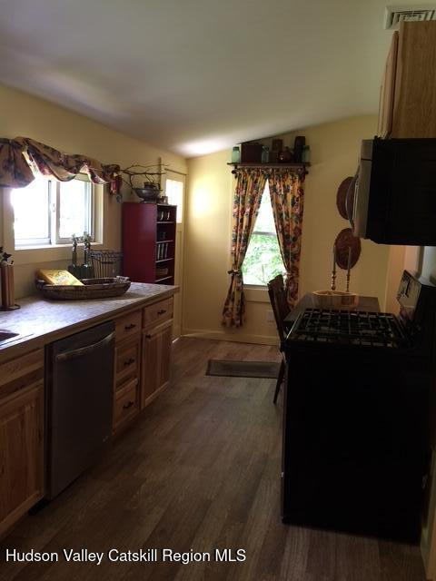 kitchen featuring lofted ceiling, dark wood-style floors, visible vents, and stainless steel dishwasher